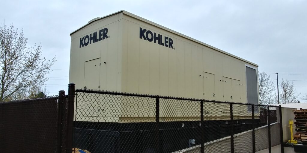 A tan Kohler generator fully-installed behind a chain link fence