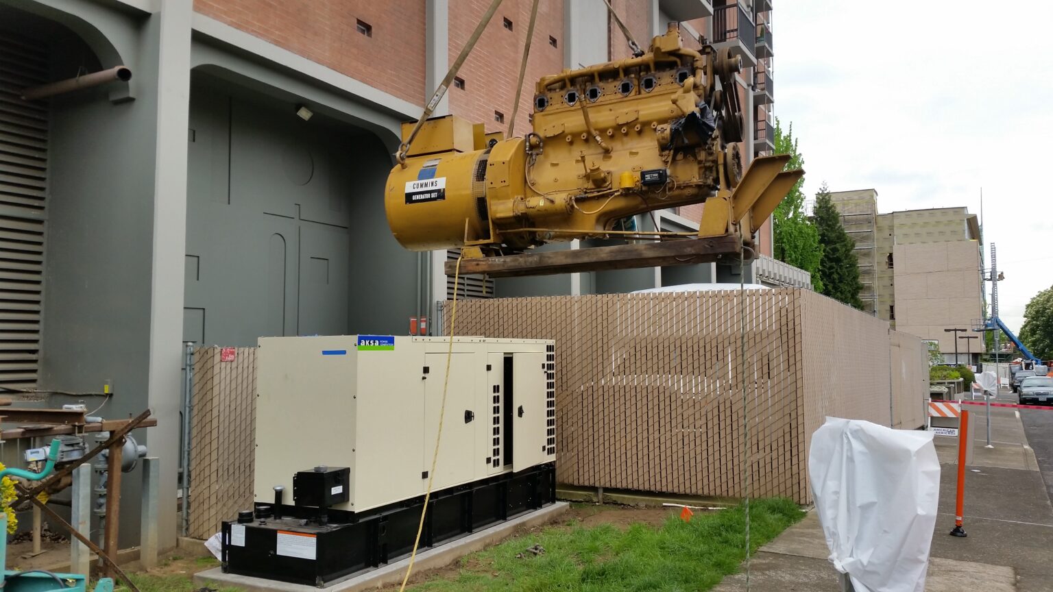 A yellow cummins generator being replaced with an ASKA standby generator